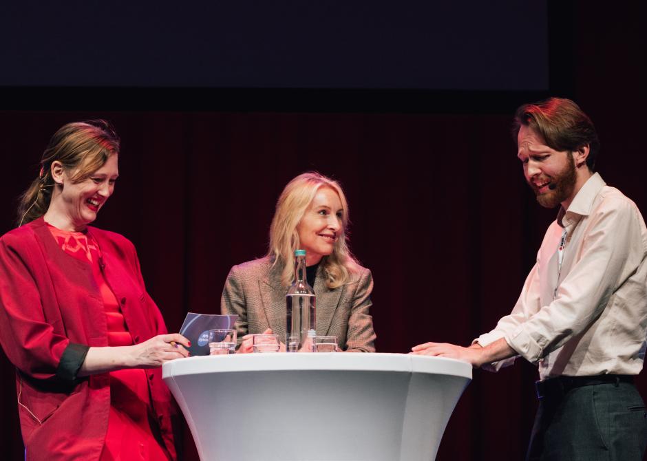 To kvinner og en mann står på scenen.